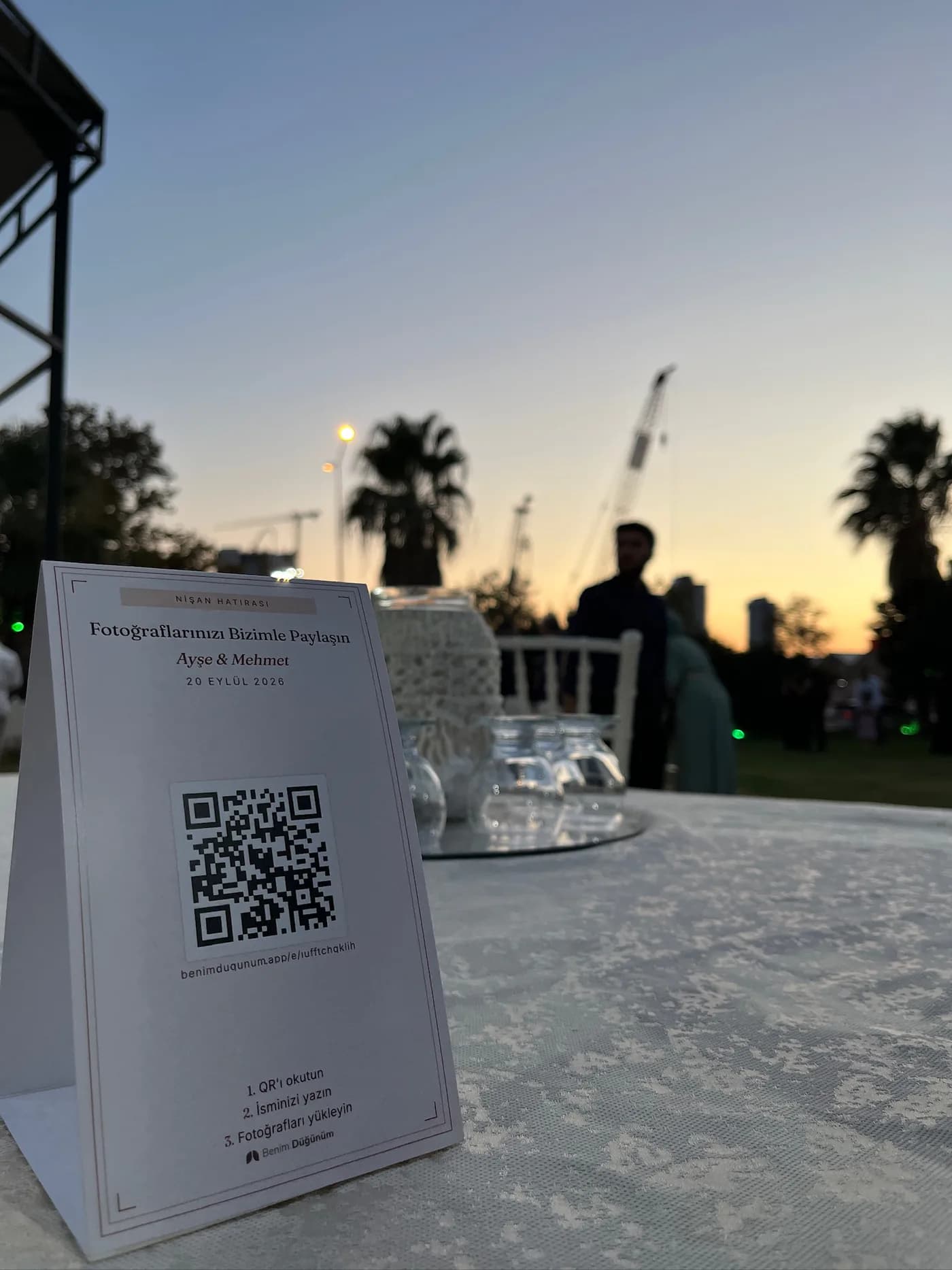 Gün batımında masaya yerleştirilmiş fiziksel Benim Düğünüm QR kartı